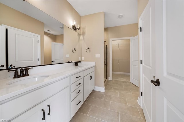 full bath featuring double vanity, a stall shower, tile patterned floors, a spacious closet, and a sink