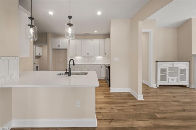 kitchen featuring sink, white cabinetry, light wood-type flooring, and tasteful backsplash