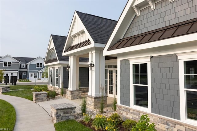 exterior space with stone siding, a shingled roof, metal roof, and a standing seam roof