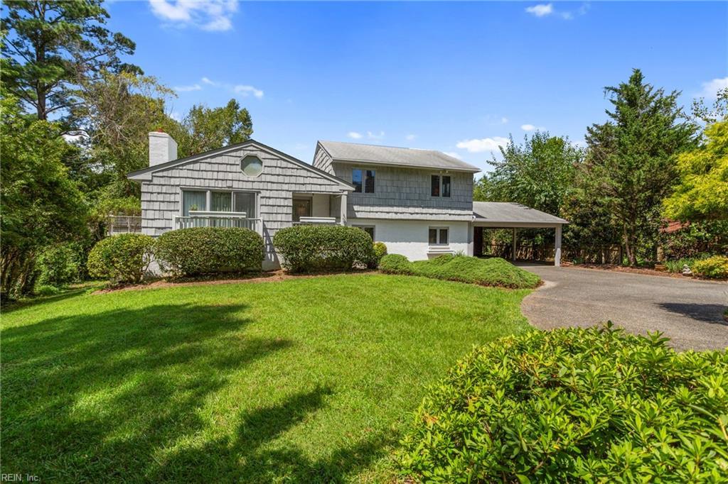 view of front of home featuring an attached carport, driveway, a chimney, and a front lawn