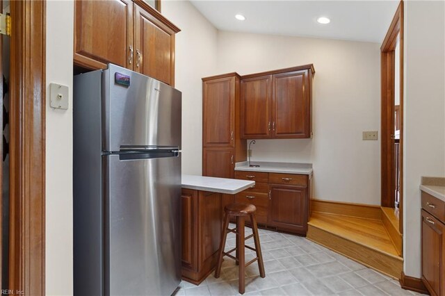 kitchen featuring a kitchen bar, stainless steel fridge, light hardwood / wood-style flooring, and lofted ceiling