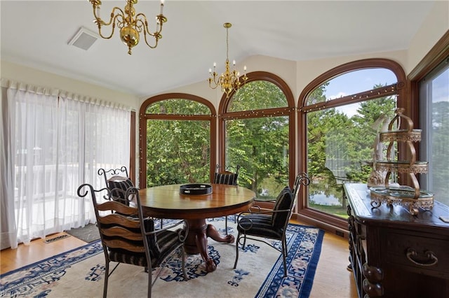 dining area with a notable chandelier, vaulted ceiling, and light wood-type flooring