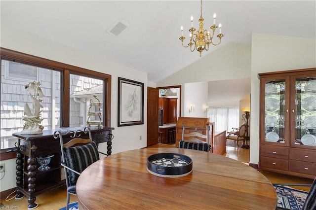 dining room with vaulted ceiling, an inviting chandelier, and light wood-type flooring