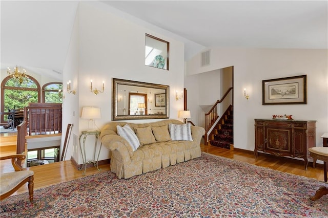 living room featuring hardwood / wood-style flooring, a notable chandelier, and high vaulted ceiling