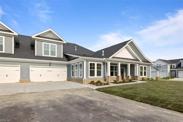 view of front of home featuring aphalt driveway, a porch, a garage, brick siding, and a front yard