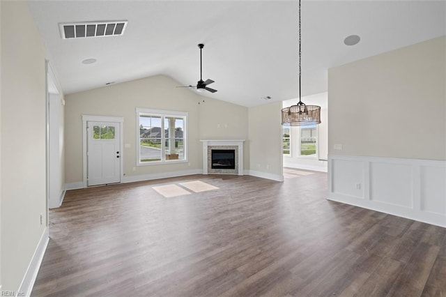 unfurnished living room featuring ceiling fan, a fireplace, visible vents, vaulted ceiling, and dark wood finished floors