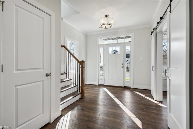 foyer featuring crown molding, a barn door, and dark wood-type flooring