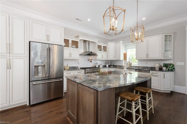 kitchen with a center island, stainless steel appliances, wall chimney range hood, and white cabinets