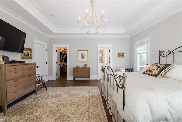 bedroom featuring ornamental molding, a tray ceiling, and a walk in closet