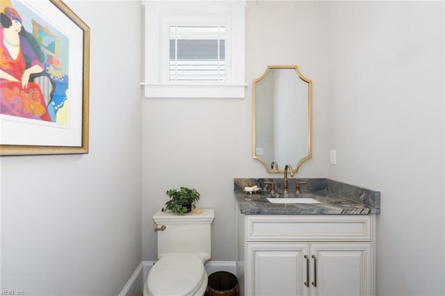 bathroom with toilet, vanity, and baseboards