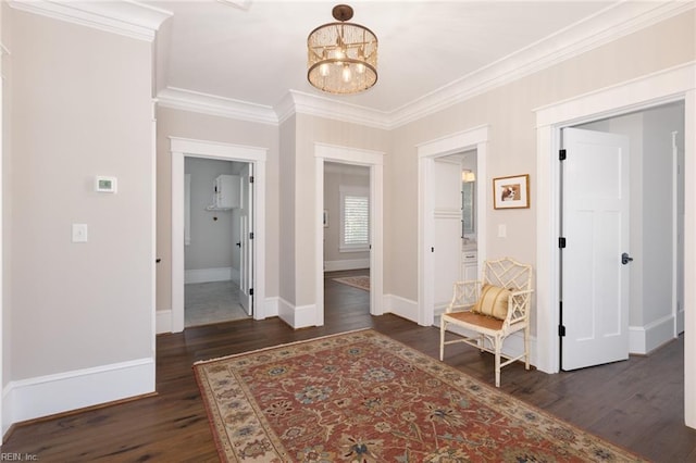 corridor with baseboards, ornamental molding, dark wood finished floors, and a notable chandelier