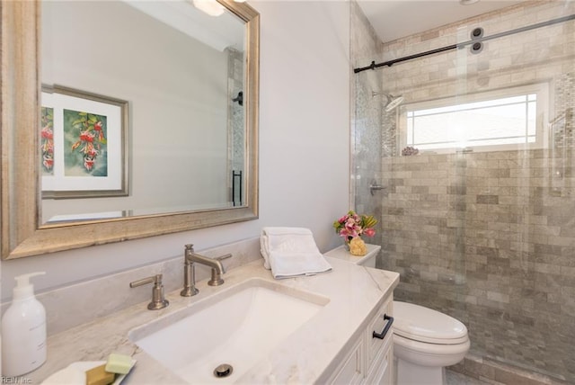 full bathroom with toilet, tiled shower, and vanity