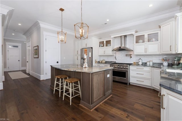 kitchen with wall chimney range hood, decorative backsplash, appliances with stainless steel finishes, and white cabinets