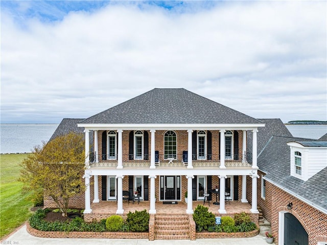 view of front of house featuring a balcony, covered porch, and a water view