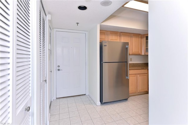 kitchen with stainless steel fridge, light tile patterned flooring, and light brown cabinets