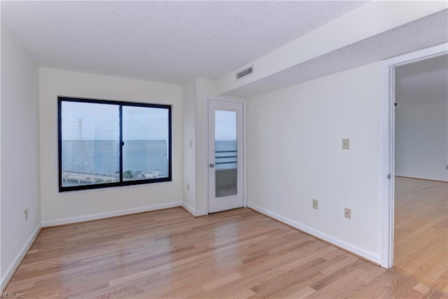 empty room featuring a textured ceiling and light hardwood / wood-style floors