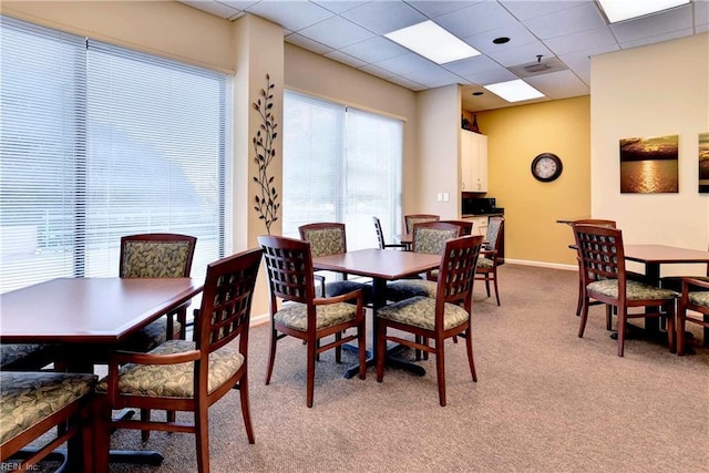 dining area with a drop ceiling and light colored carpet