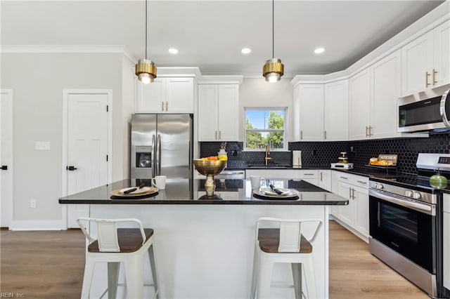 kitchen featuring decorative light fixtures, a center island, stainless steel appliances, and sink