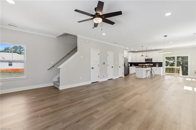 unfurnished living room featuring crown molding, plenty of natural light, and hardwood / wood-style floors