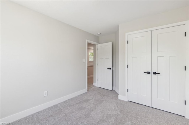 unfurnished bedroom featuring light carpet and a closet