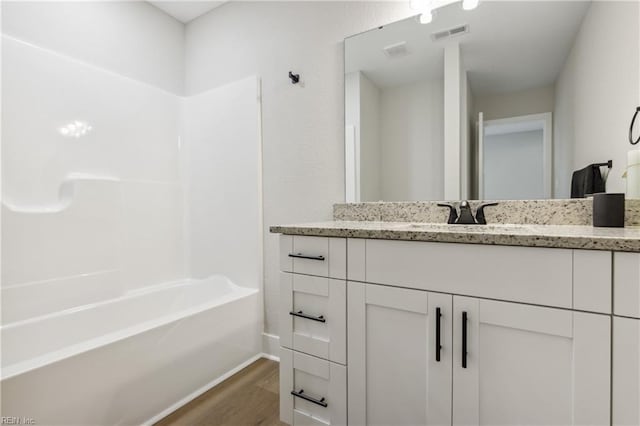 bathroom with vanity, wood-type flooring, and washtub / shower combination