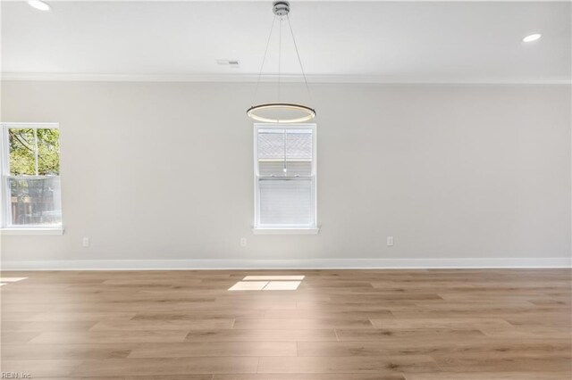 empty room featuring light wood-type flooring and crown molding