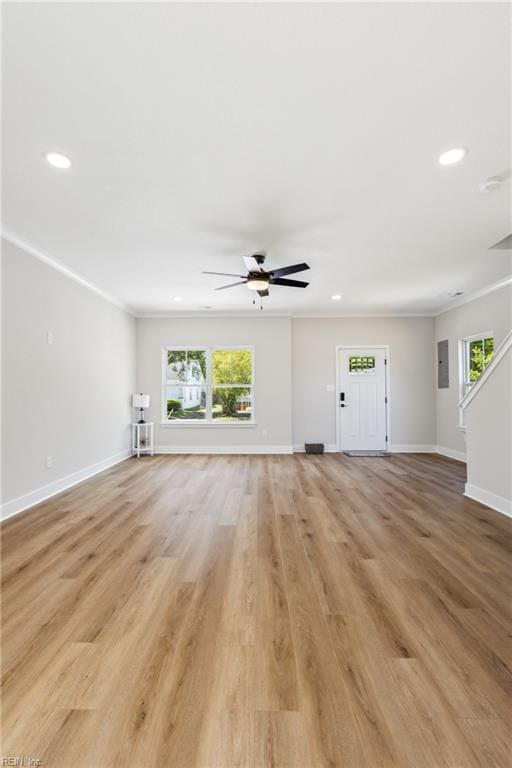 unfurnished living room featuring light hardwood / wood-style floors, a wealth of natural light, and ornamental molding