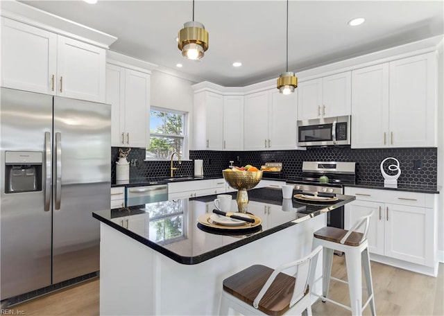 kitchen with decorative backsplash, white cabinets, stainless steel appliances, and decorative light fixtures