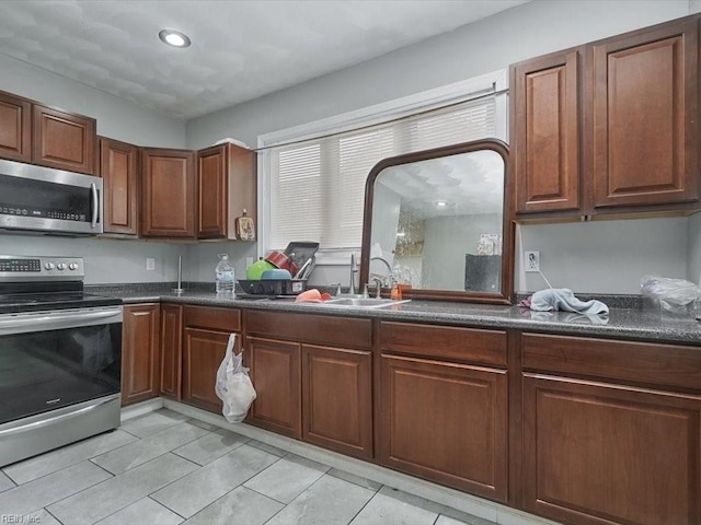 kitchen featuring appliances with stainless steel finishes, light tile patterned floors, sink, and dark stone counters