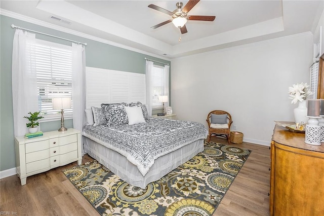 bedroom featuring ceiling fan, hardwood / wood-style floors, a raised ceiling, and crown molding