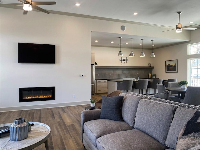 living room featuring ceiling fan, ornamental molding, and dark hardwood / wood-style floors