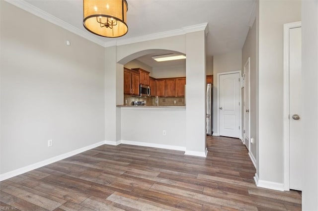 interior space featuring ornamental molding, kitchen peninsula, hardwood / wood-style flooring, and tasteful backsplash