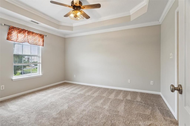 empty room featuring a tray ceiling, ornamental molding, carpet, and ceiling fan