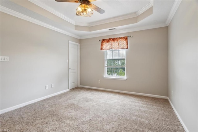 carpeted spare room with a raised ceiling, ceiling fan, and ornamental molding