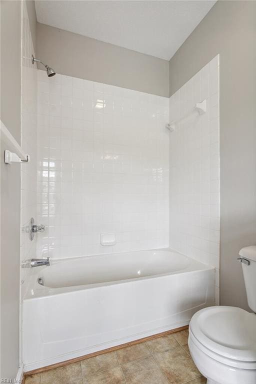 bathroom featuring tiled shower / bath, toilet, and tile patterned floors