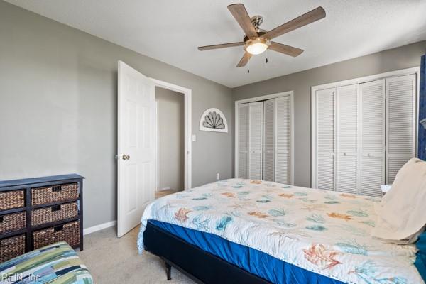 bedroom featuring ceiling fan, two closets, and light colored carpet