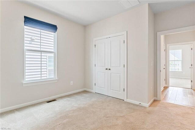 unfurnished bedroom featuring light colored carpet and a closet