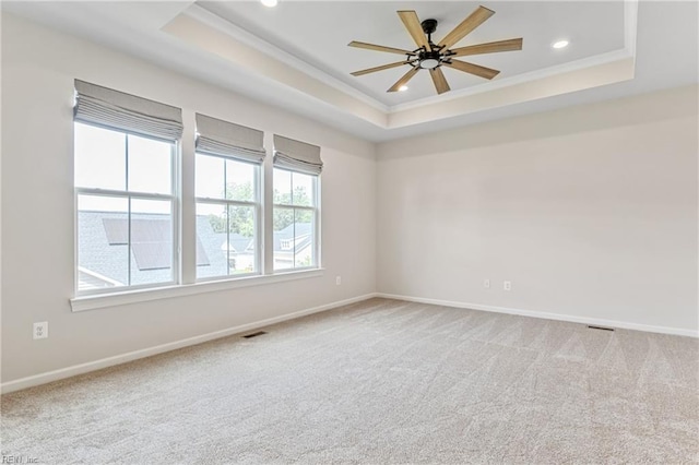 spare room featuring carpet, ceiling fan, and a tray ceiling