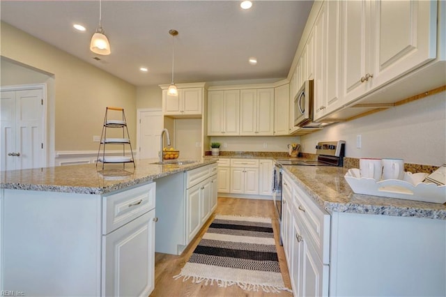 kitchen featuring pendant lighting, stainless steel appliances, white cabinetry, and sink