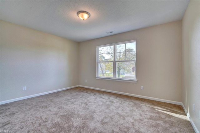 carpeted empty room featuring visible vents, baseboards, and a textured ceiling