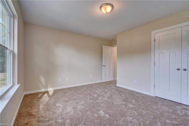 unfurnished bedroom with carpet flooring, baseboards, a closet, and a textured ceiling