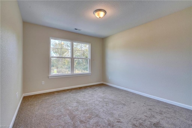 carpeted empty room featuring baseboards, visible vents, a textured wall, and a textured ceiling