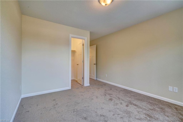 unfurnished bedroom featuring a spacious closet, light carpet, and a closet