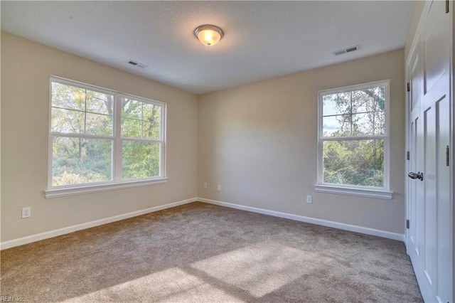 carpeted spare room with visible vents, a textured ceiling, and baseboards