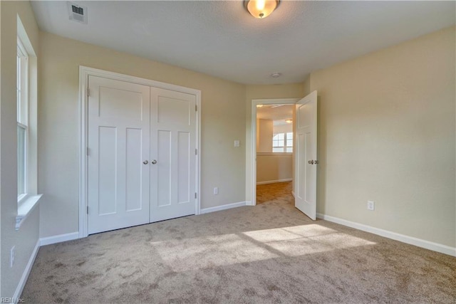 unfurnished bedroom featuring carpet, visible vents, a closet, and baseboards