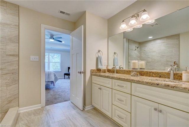 ensuite bathroom featuring double vanity, visible vents, tiled shower, and a sink