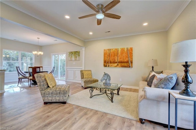 living room with recessed lighting, ceiling fan with notable chandelier, crown molding, and light wood finished floors