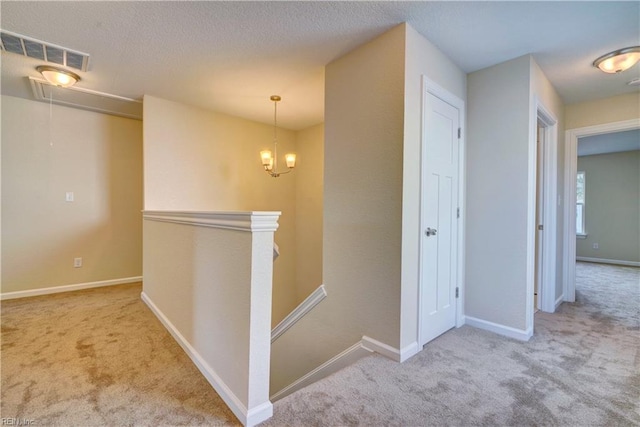 hall with an upstairs landing, visible vents, baseboards, and carpet