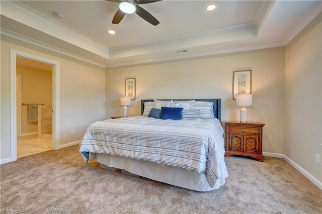 carpeted bedroom with a tray ceiling, ceiling fan, ensuite bathroom, and ornamental molding