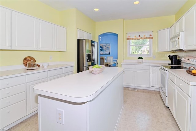 kitchen featuring a kitchen island, white appliances, white cabinetry, and light tile patterned floors